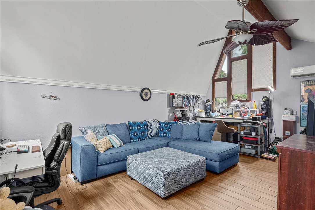 Living room with a blue sectional, patterned ottoman, vaulted ceiling, and tall windows.