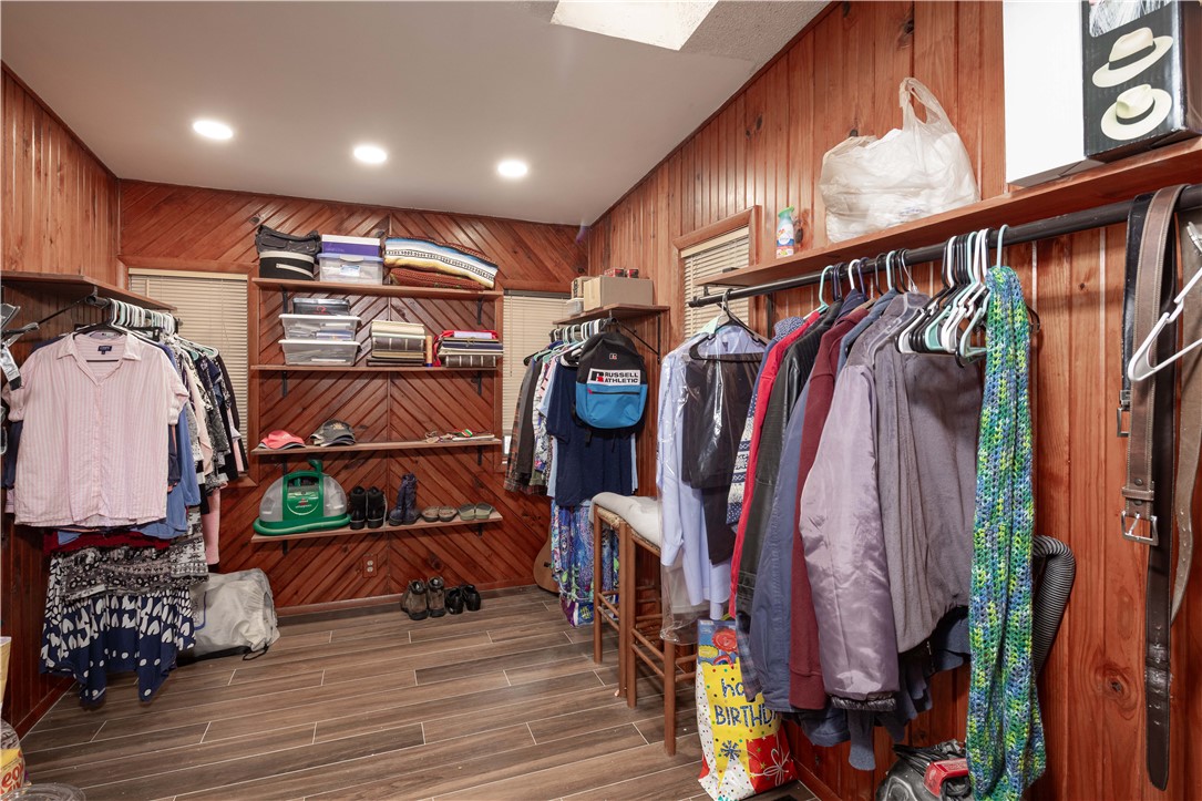 Walk-in closet with wood-paneled walls, clothes racks, and storage shelves.