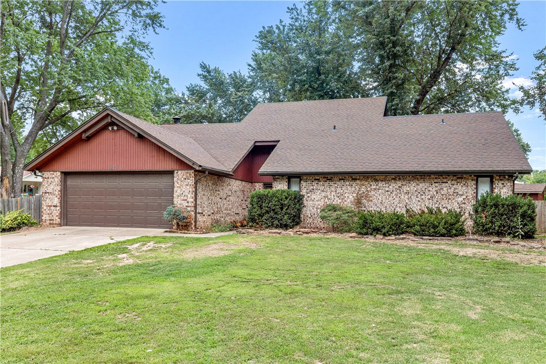Single-story brick home with red gable siding, an attached garage, and a broad front lawn.