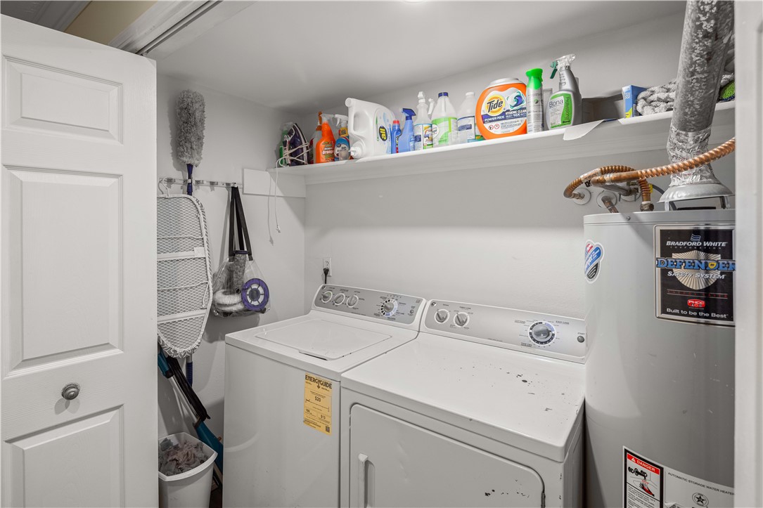 Laundry room with washer, dryer, cleaning supplies on a shelf, and a water heater.
