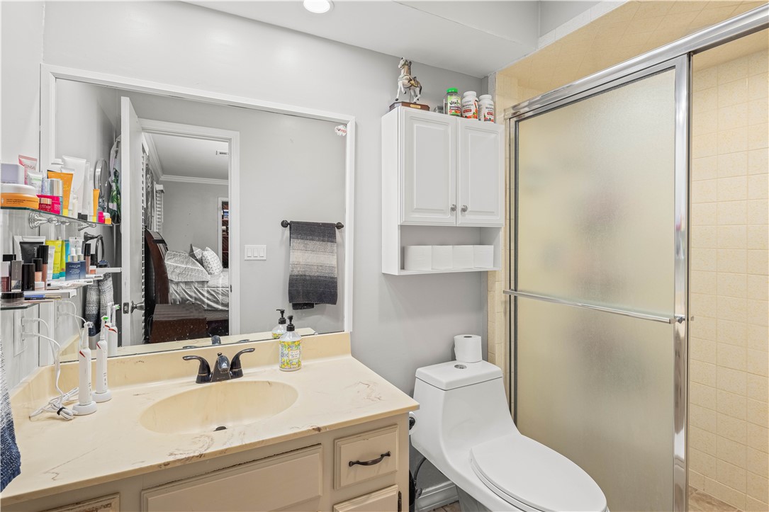 Bathroom with a cream vanity, white toilet, and frosted-glass shower.