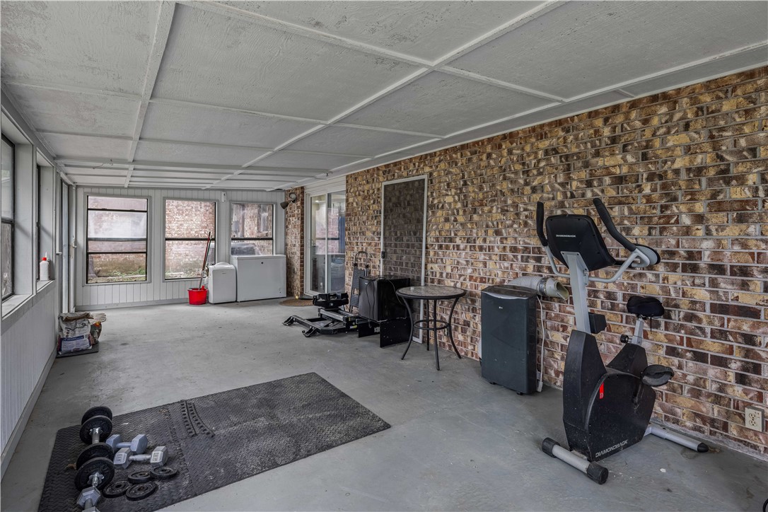 Home gym with a brick wall, large windows, exercise bike, and free weights.