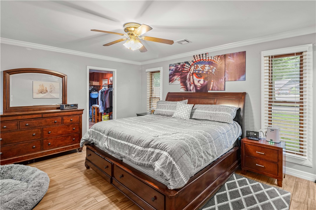 Bedroom with a dark wood bed, gray patterned bedding, ceiling fan, and open closet.