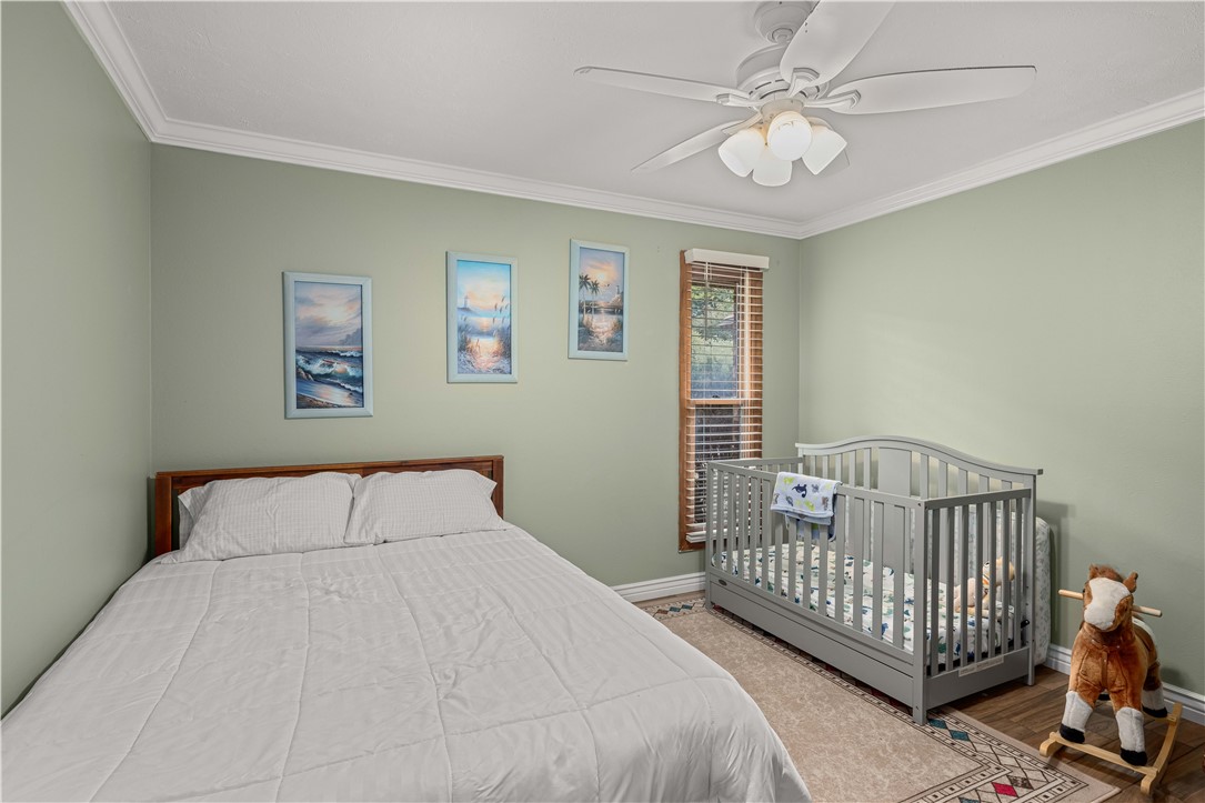 Bedroom with a large bed, gray baby crib, and framed coastal art.