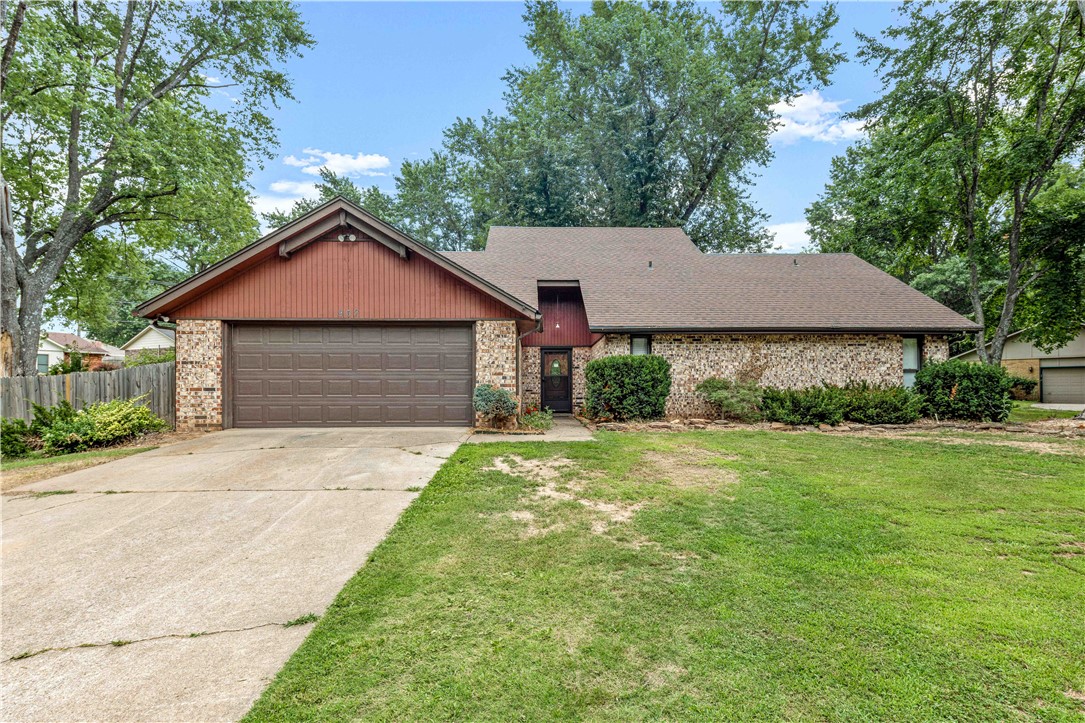 Brick home with a red front gable, two-car garage, driveway, and mature trees.