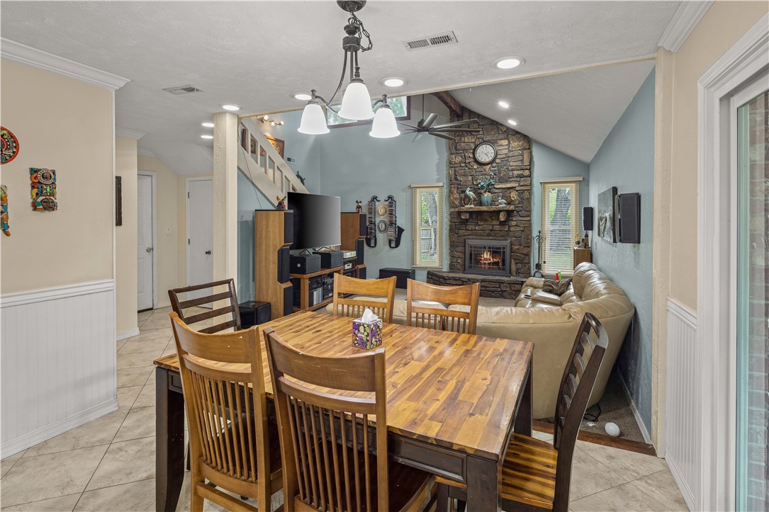 Open-plan dining and living room with a wood table, tan sectional, and stone fireplace.