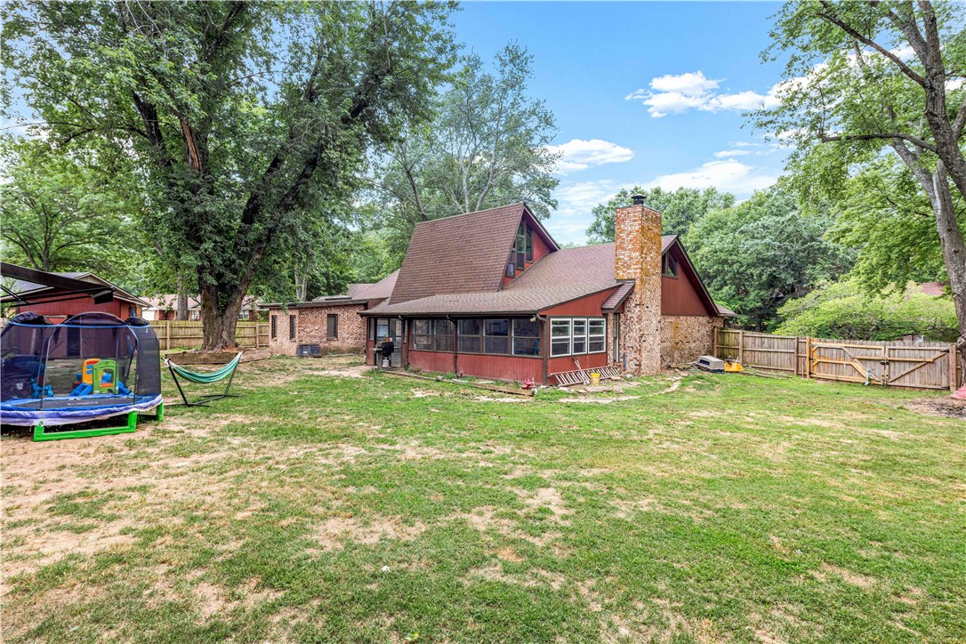 Rear exterior of a brick-and-wood home with a screened porch and fenced yard.