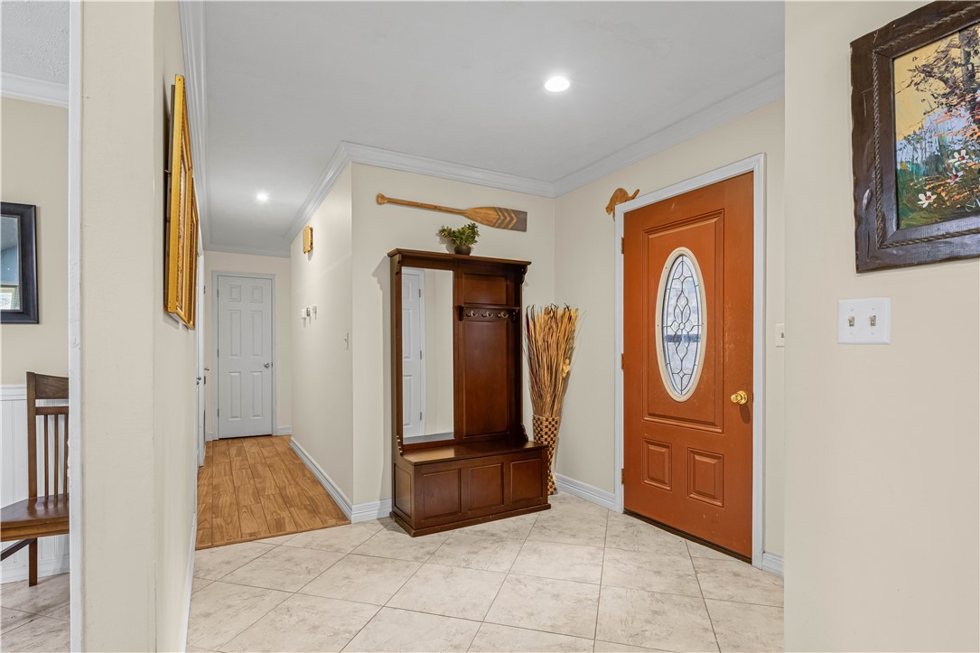 Entry foyer with an oval-glass front door, tiled floor, and dark wood hall tree.