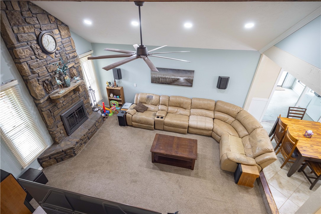 Furnished living room with a tan sectional sofa and prominent stone fireplace.
