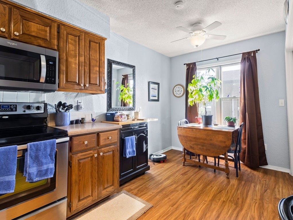Kitchen with warm wood cabinets, stainless steel appliances, and a small dining table by the window.