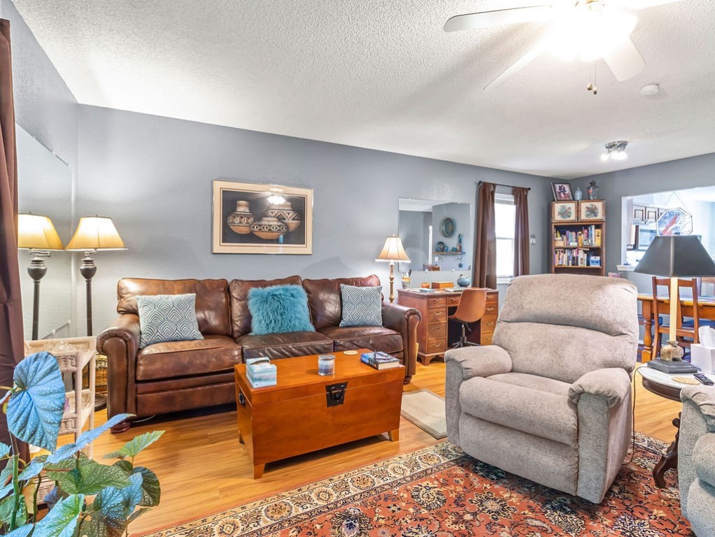 Living room with a brown leather sofa, gray recliner, hardwood floors, and patterned rug.