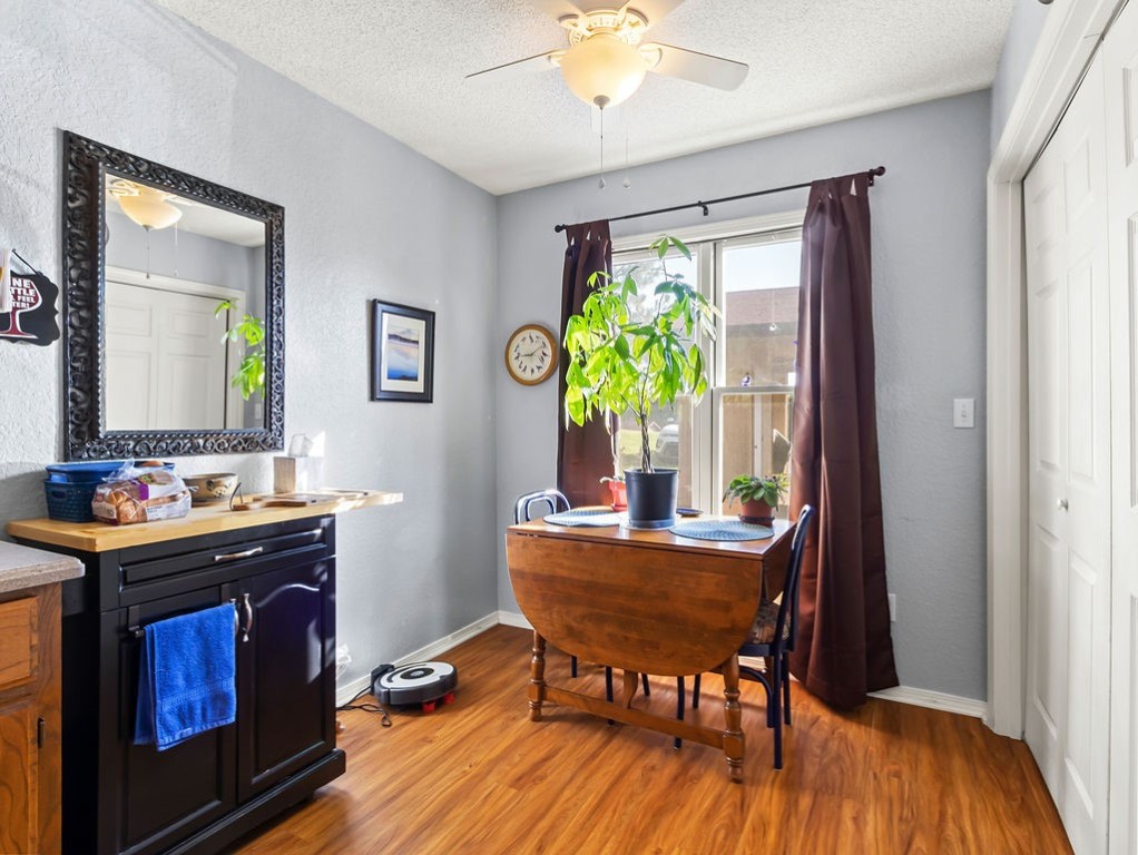 Dining area with a wooden table by a curtained window and a dark sideboard with a large mirror.