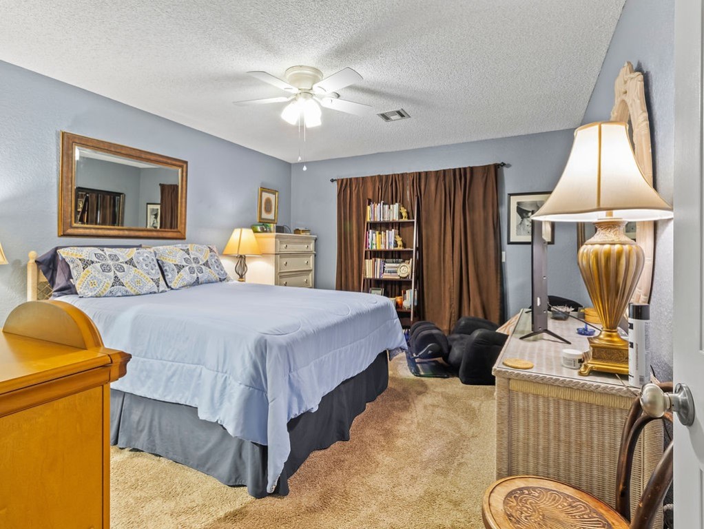 Furnished bedroom with a large bed, brown curtains, and a bookcase.