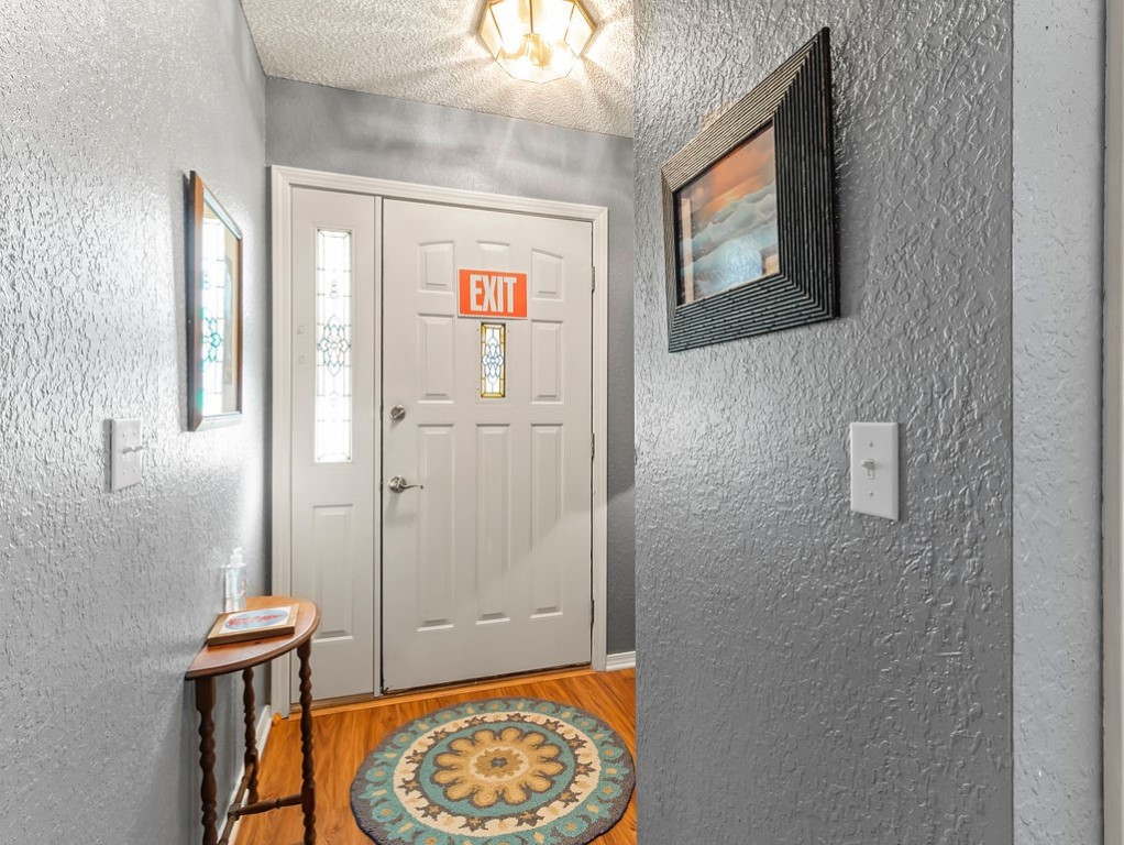 Entryway with a white glass-panel door, round patterned rug, and small wooden table.