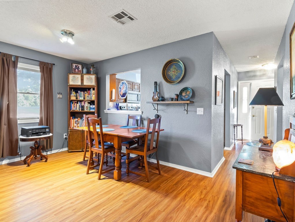 Dining room with a wooden table, bookcase, and pass-through to the kitchen.