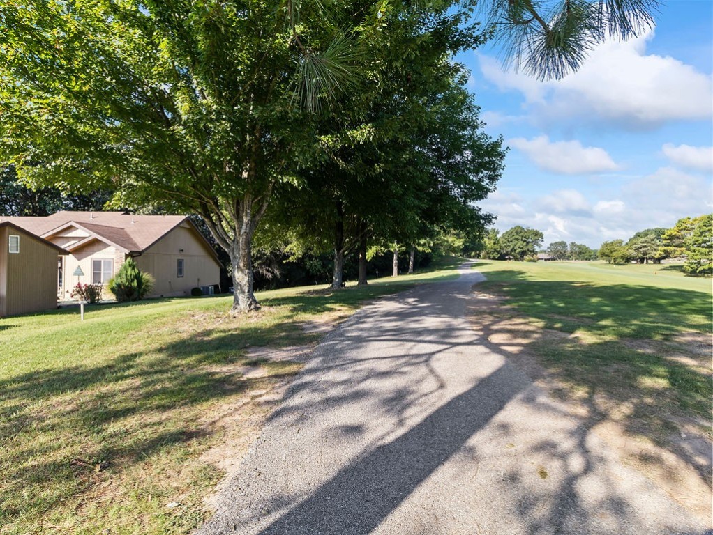 Home beside a golf course, with a paved path and mature trees along the fairway.