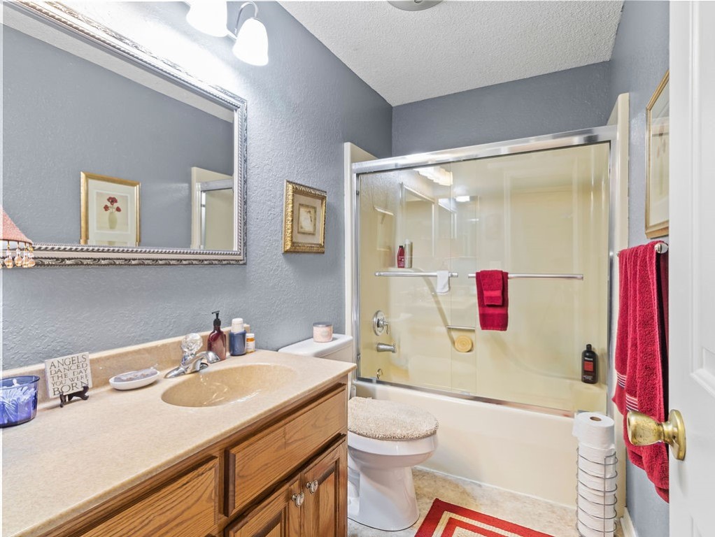 Bathroom with a wood vanity, large framed mirror, and bathtub with glass shower doors.