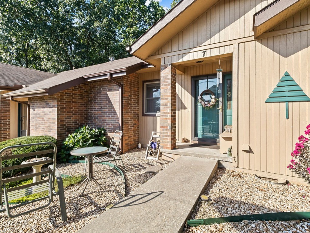 Home entrance with teal door, covered porch, and gravel courtyard seating.