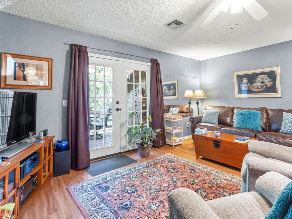 Living room with a leather sofa, patterned rug, and French doors opening to a patio.