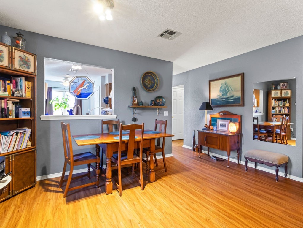 Dining room with a wooden table, gray walls, maritime art, and a built-in bookcase.