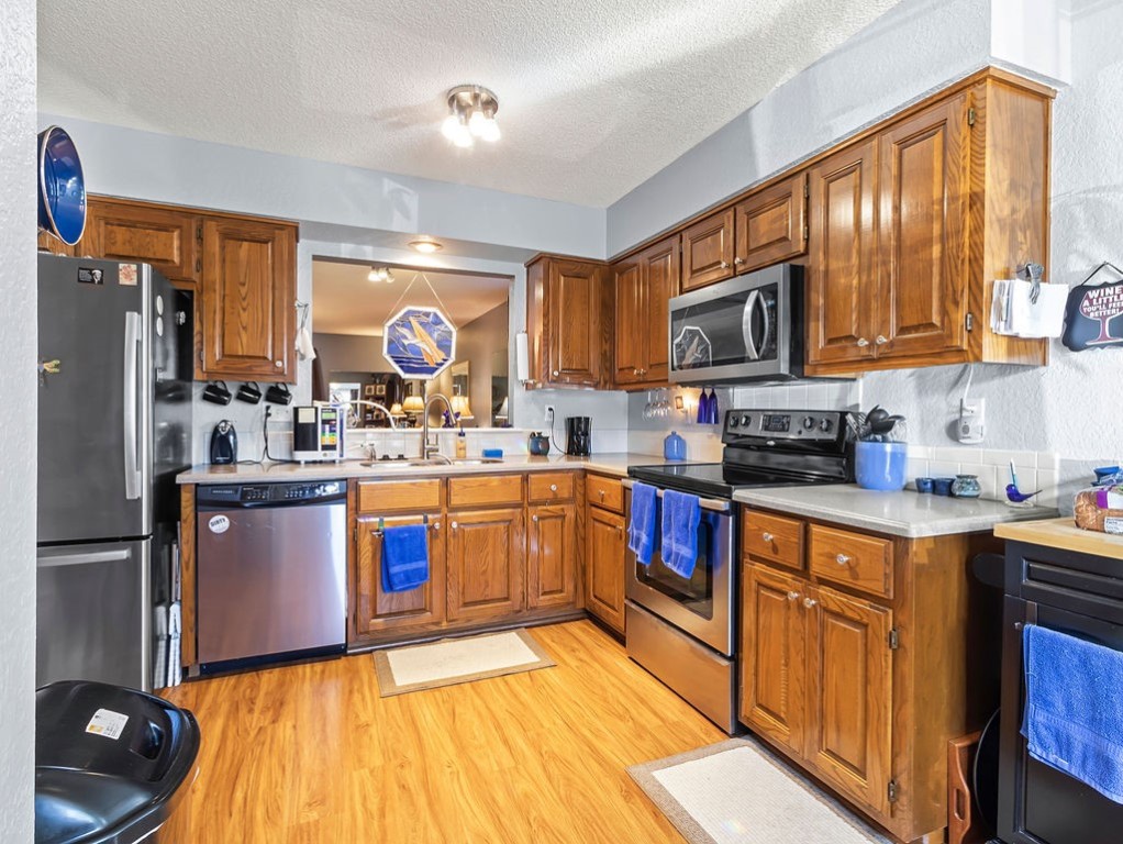 Kitchen with warm wood cabinets, stainless steel appliances, and wood flooring.