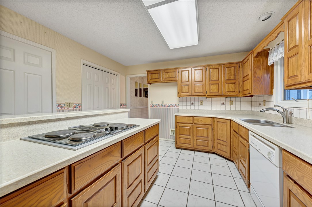 Kitchen with honey-colored wood cabinets, a four-burner cooktop, and light countertops.
