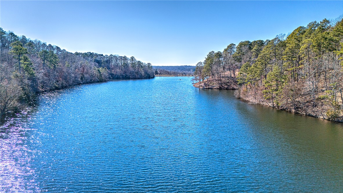 Blue lake bordered by wooded shores and a small tree-covered peninsula.