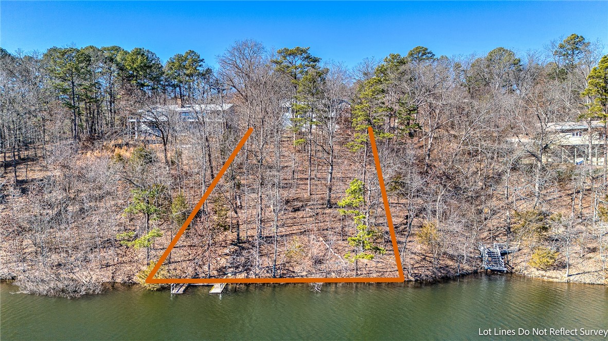 Aerial view of a wooded waterfront lot outlined in orange beside the lake.