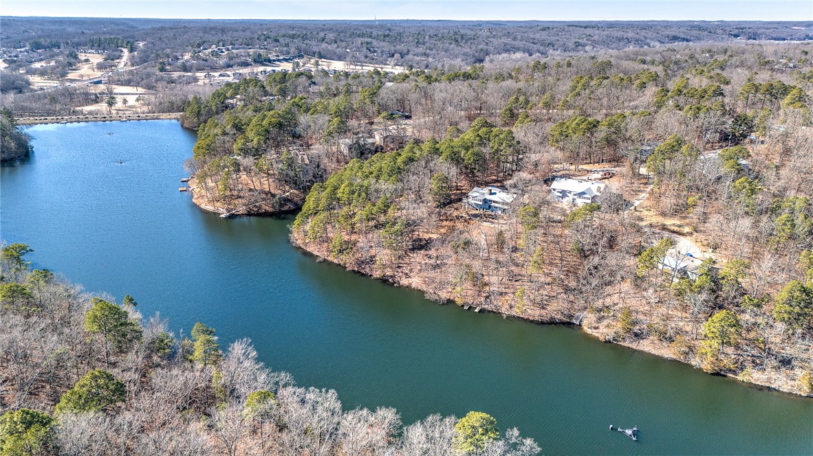 Aerial view of homes along a wooded lake, with a broad inlet and mostly leafless trees.