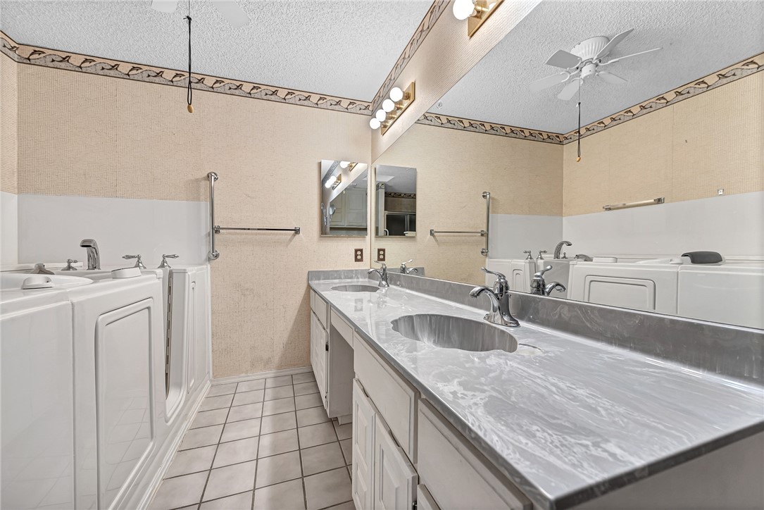 Bathroom with long marble-look double vanity, mirrored wall, and two front-loading laundry machines.