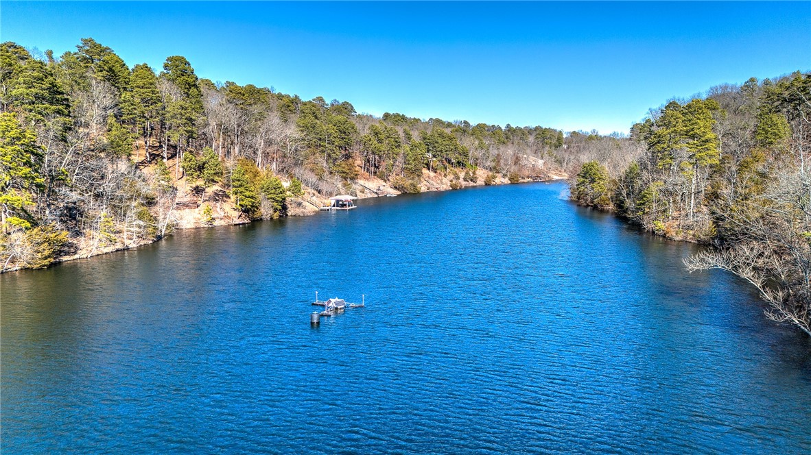 Blue lake bordered by wooded shores, with a small dock floating near the center.