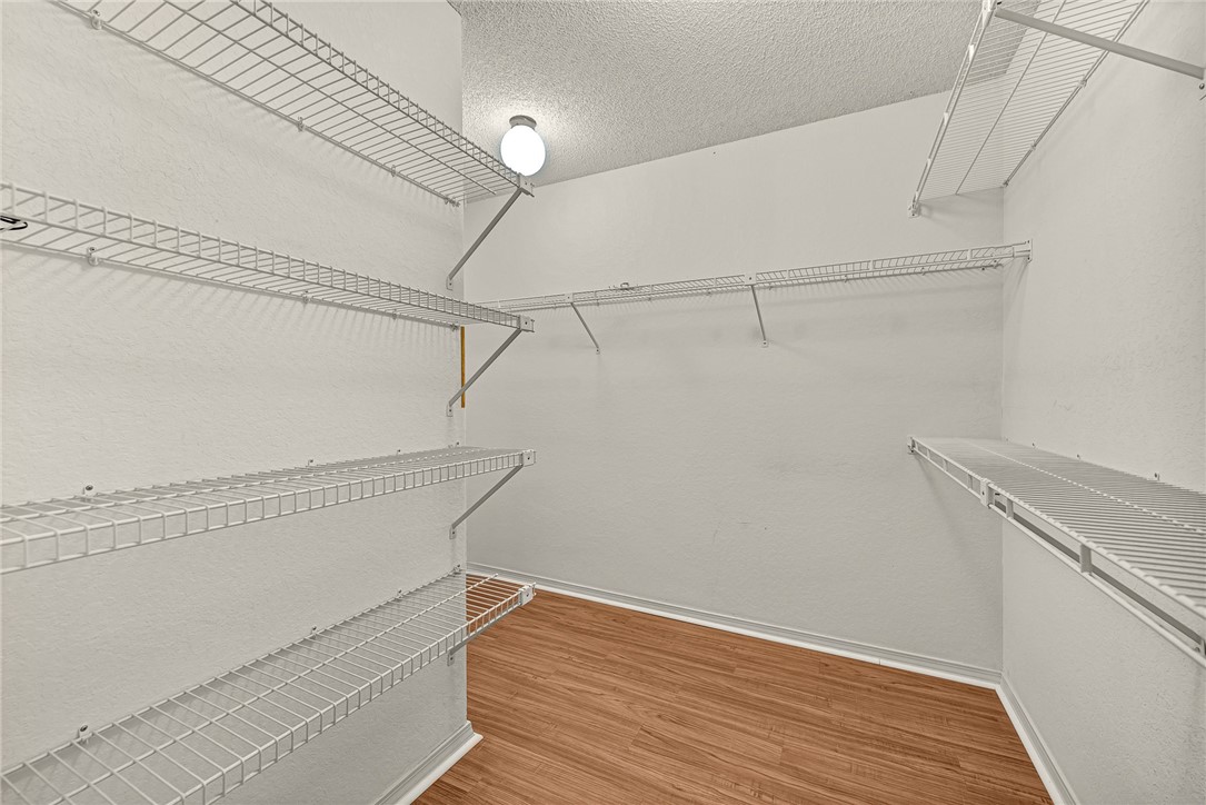 Walk-in closet with white wire shelving and wood-look flooring.