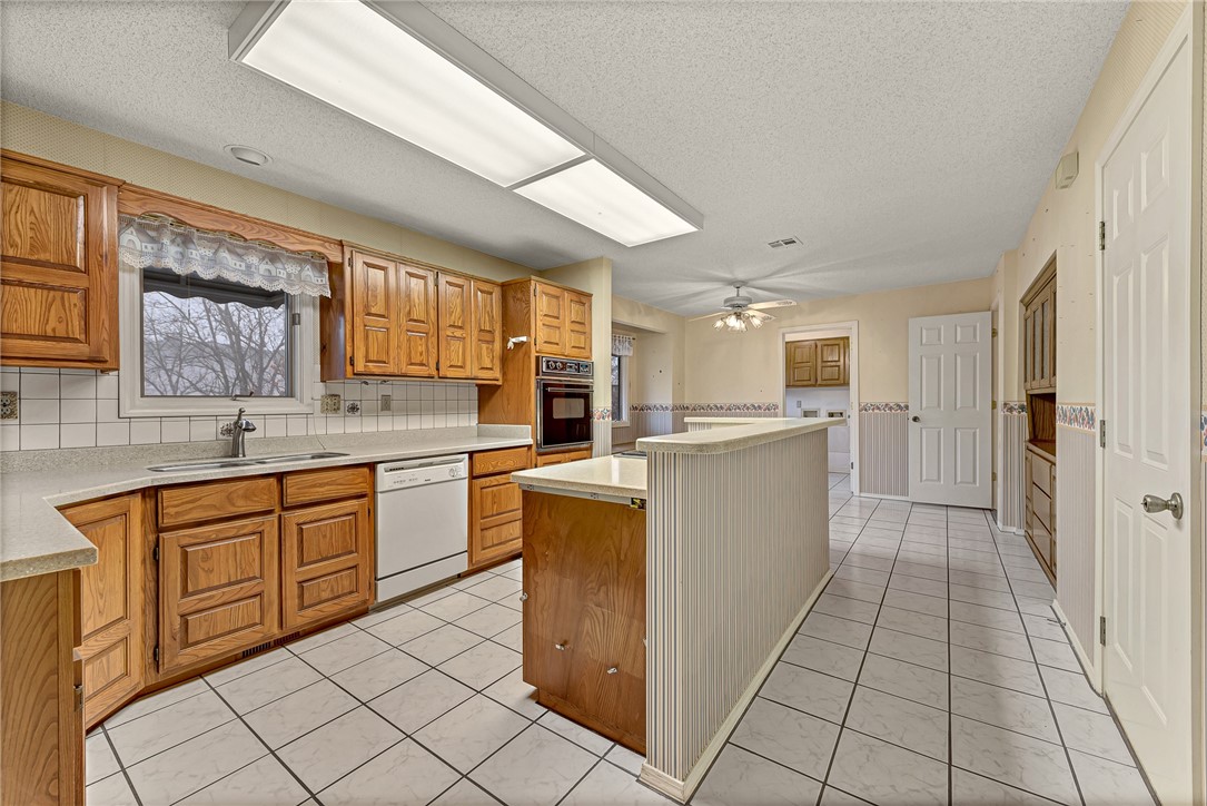 Kitchen with warm wood cabinets, tiled floors, and a long central island.