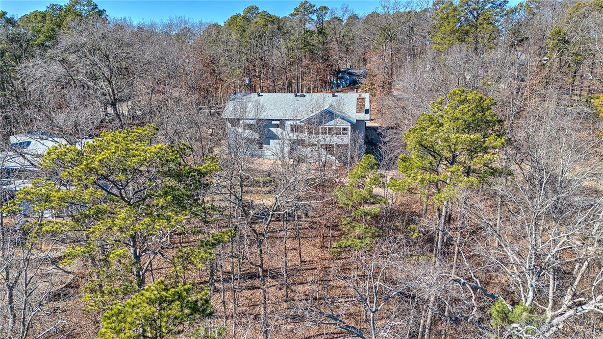 House nestled among dense woodland, seen from above.