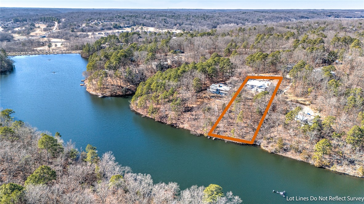 Wooded lakefront property outlined in orange, with a house near the shore.