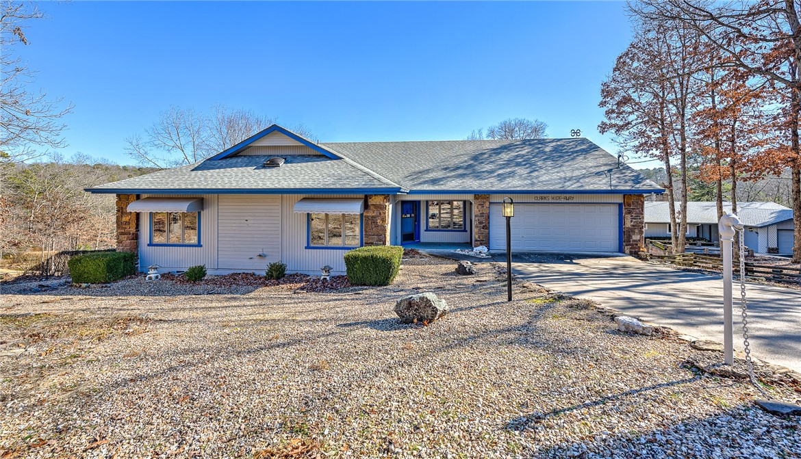 Single-story home with stone accents, blue entry door, attached garage, and gravel landscaping.