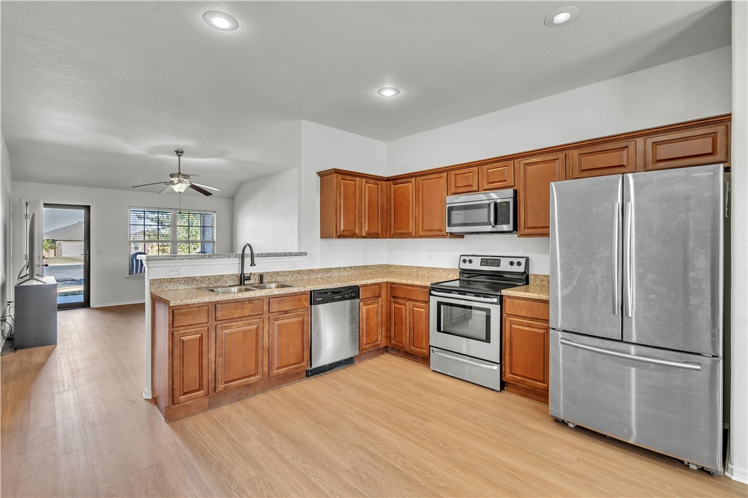 Kitchen with warm wood cabinets, stone counters, and stainless steel appliances.
