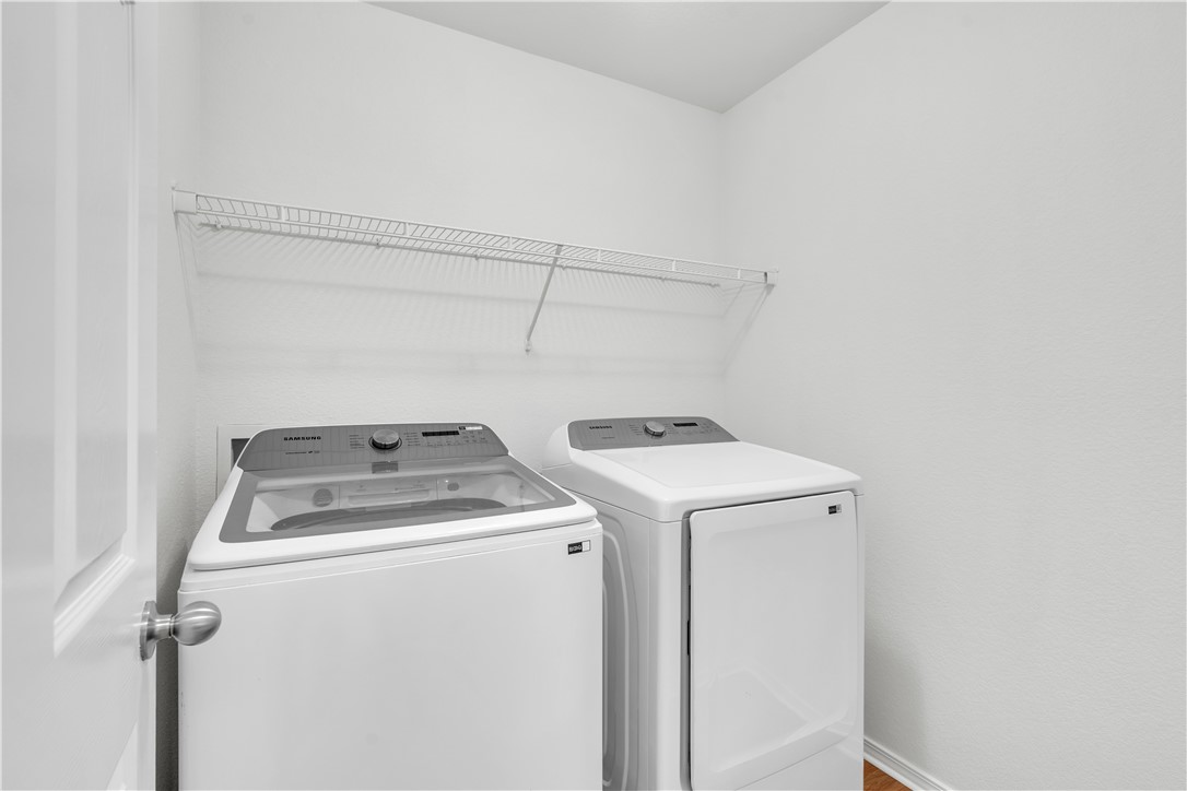 Laundry room with a Samsung washer and dryer beneath a wire storage shelf.