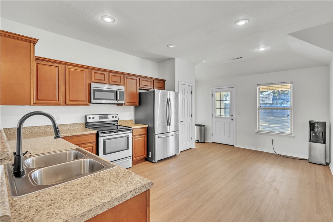 Vacant kitchen with warm wood cabinets, granite counters, and stainless steel appliances.