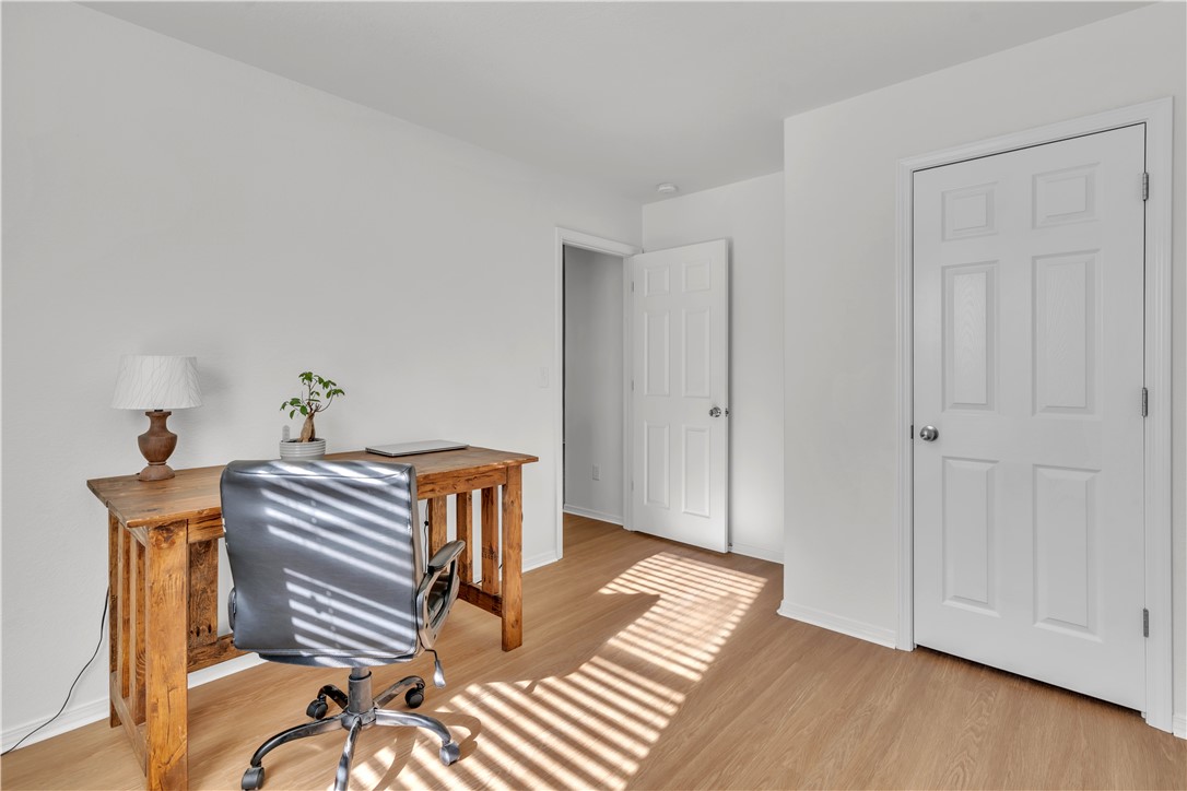 Home office with a rustic wooden desk and sunlight casting striped shadows across the floor.