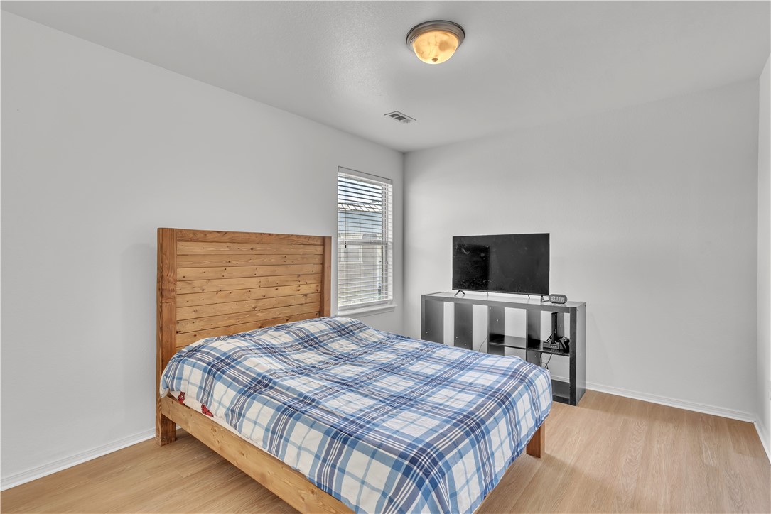 Bedroom with a wooden bed and plaid bedding, a window with blinds, and a television.