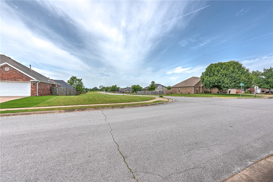 Grassy residential lot at a street corner, between brick homes.