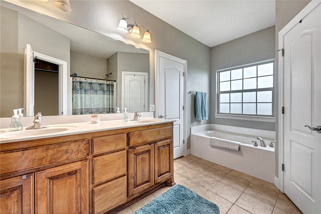 Bathroom with a wooden double vanity and bathtub beneath a large grid-pane window.
