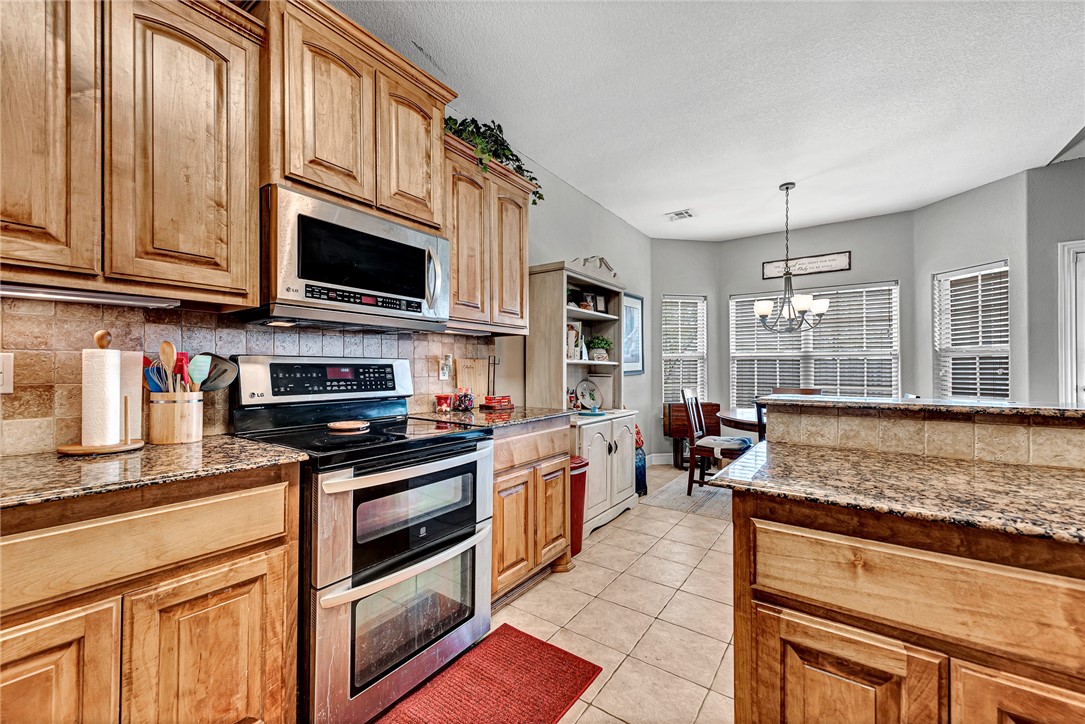 Kitchen with honey-colored cabinets, granite counters, stainless-steel appliances, and a raised breakfast bar.
