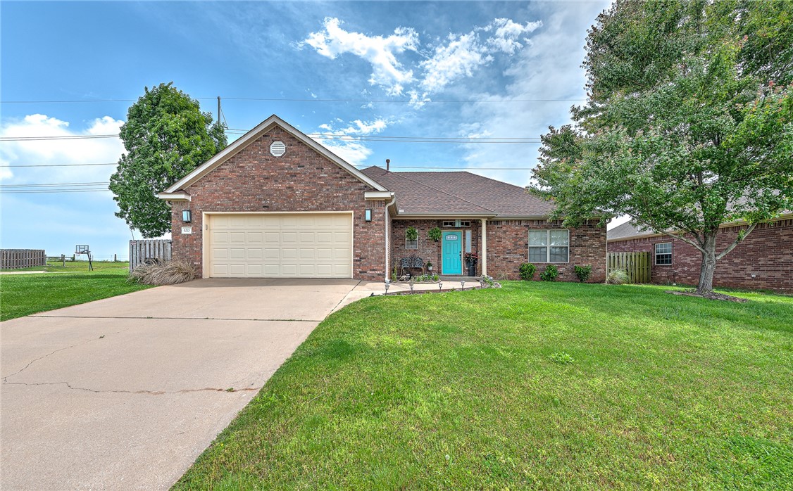 Brick house with a two-car garage, turquoise front door, and wide driveway.