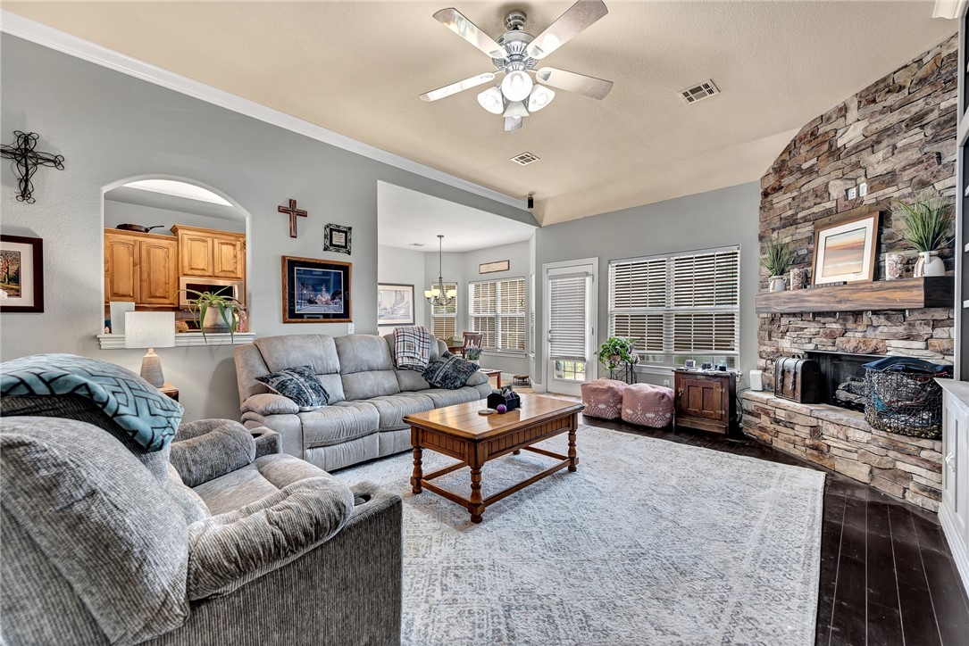 Living room with gray sofas, a stone fireplace, and an arched opening to the kitchen.