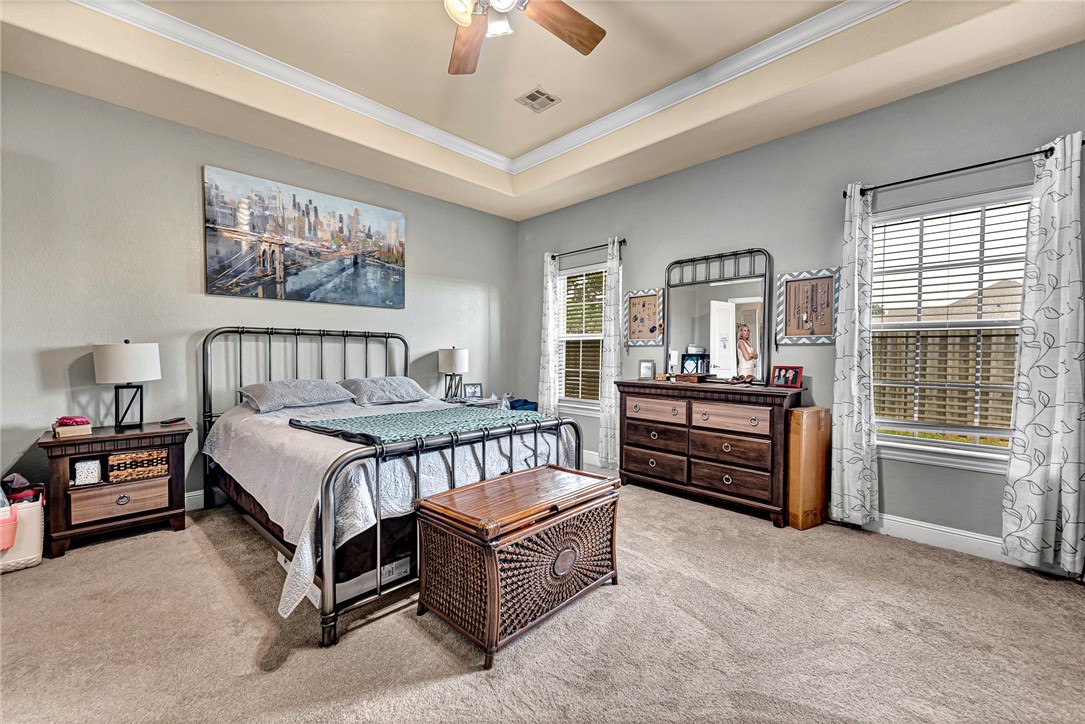 Bedroom with a black metal bed, dark wood dresser, and windows with blinds and curtains.