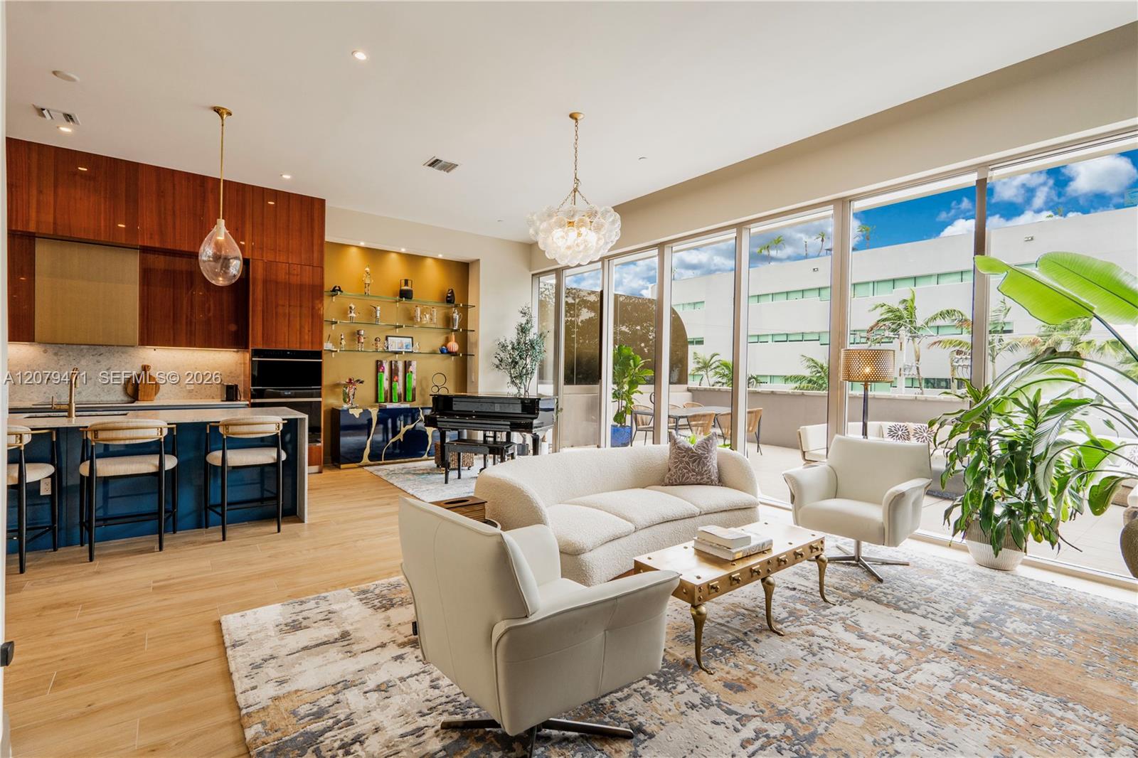 Open-plan living room and kitchen with a grand piano, dark blue cabinetry, and floor-to-ceiling windows.