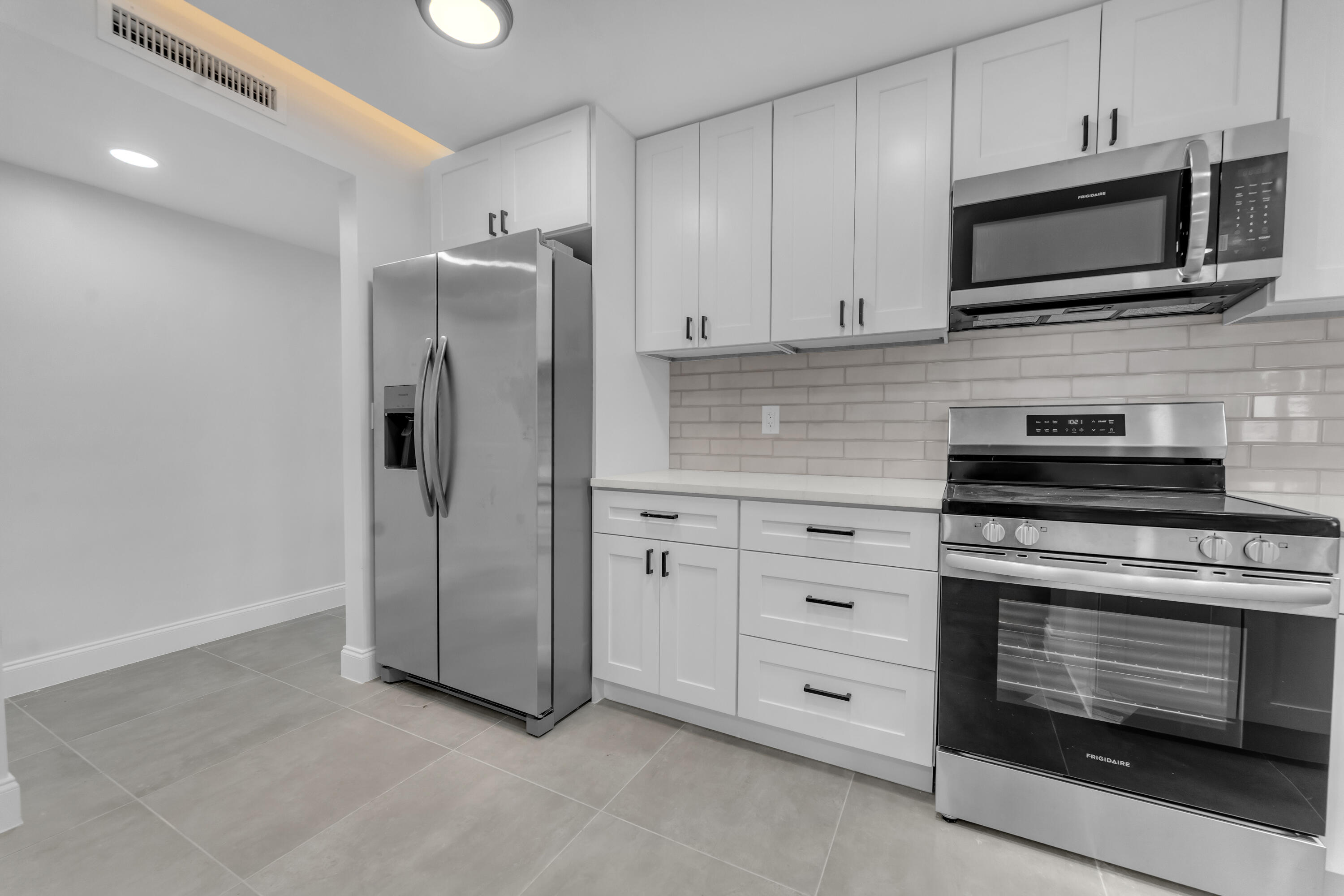 Modern kitchen with white cabinets, subway tile backsplash, and stainless steel appliances.