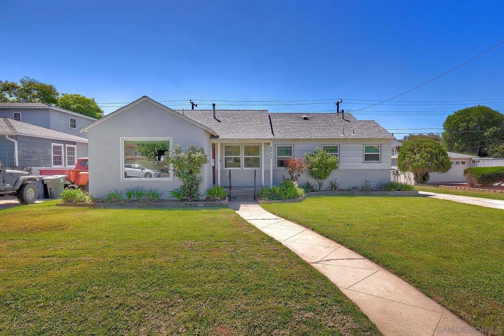 Single-story light gray house with a broad lawn and curved walkway to the entrance.